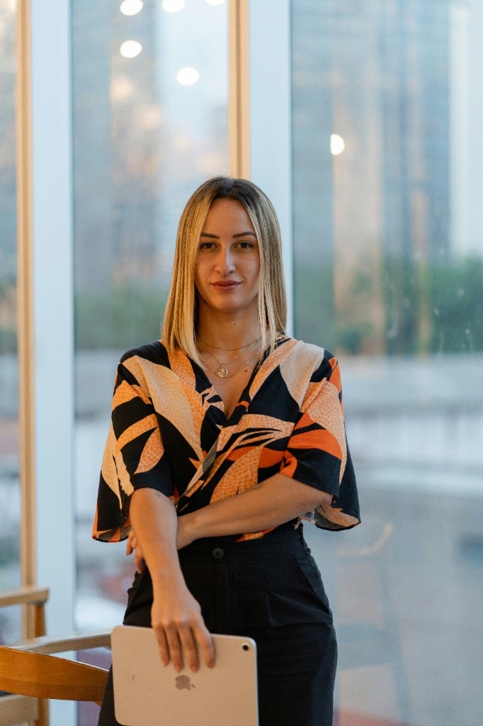 Retrato profissional de mulher com tablet em escritório com vista urbana, exemplo de assistente de RH